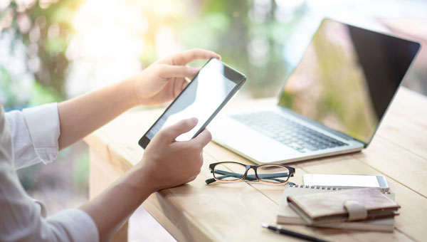 person-holding-phone-with-laptop
