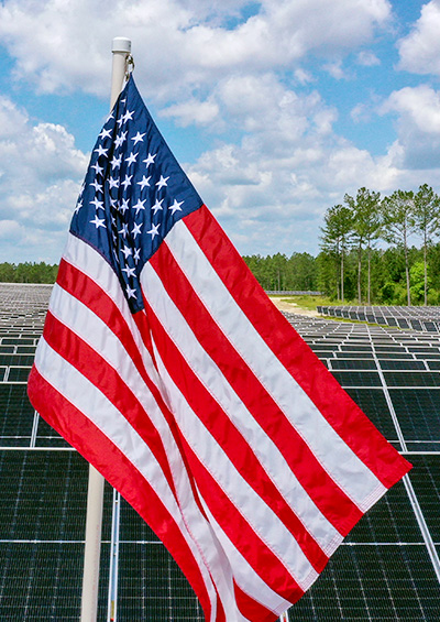 American flag with solar panels in the background