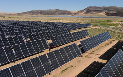 NextEra Energy solar energy center in arid terrain with tilted panels and mountains in the background.