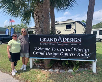 ray and beverly white next to grand design rv sign