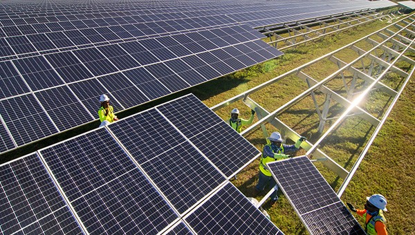 Workers installing solar panels on a solar farm