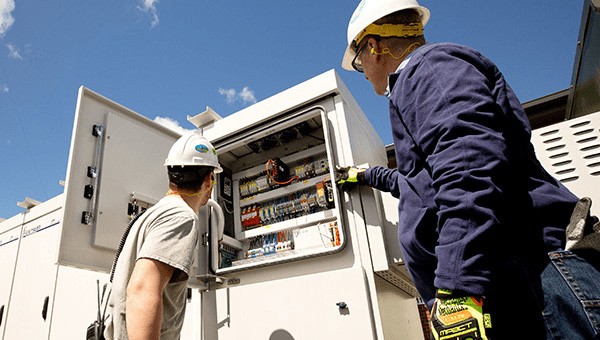 Two employees checking an electric grid