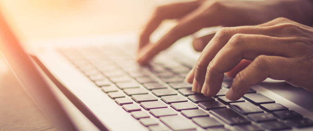 Hands typing on a laptop keyboard