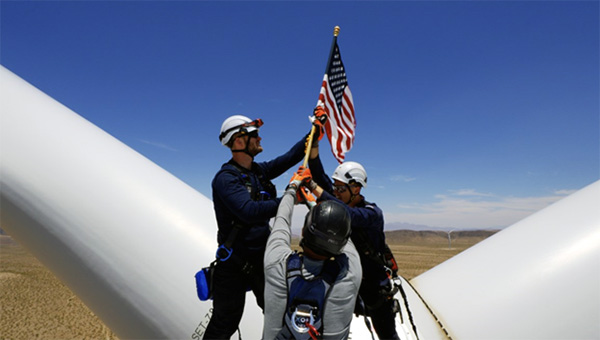Wind energy engineers placing the American flag on a wind turbine. Wind energy engineers placing the American flag on a wind turbine.